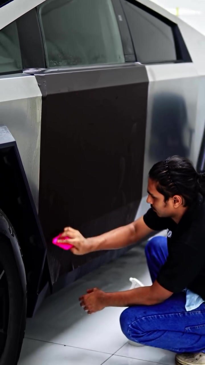 Installer fitting brown PPF on the lower door of the Tesla Cybertruck, stainless steel still visible above