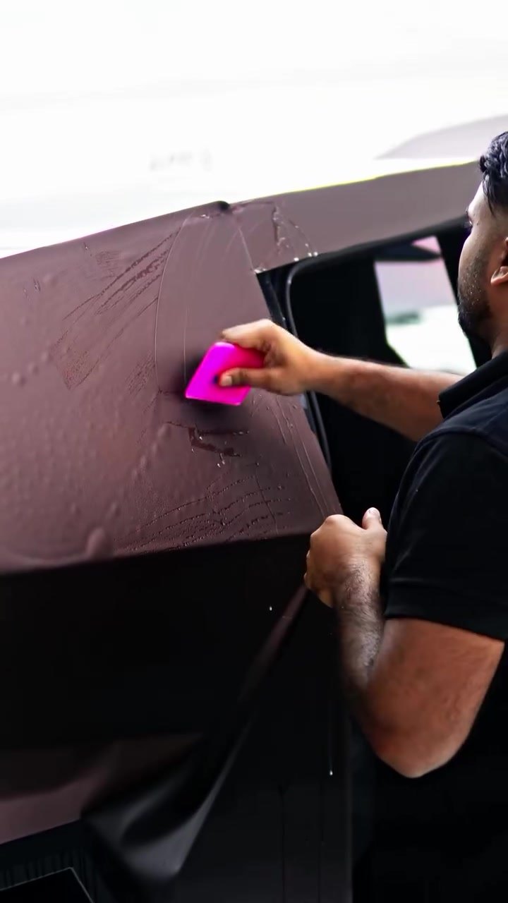 Installer squeegeeing brown colour PPF onto the Tesla Cybertruck body at Apex Detail Studio