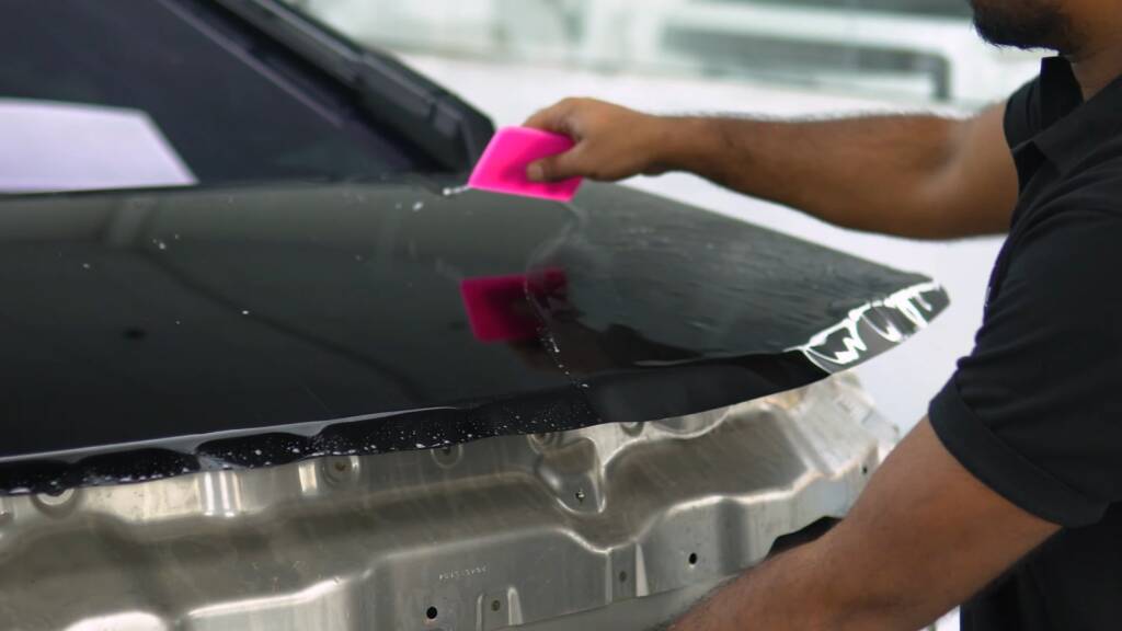 Gloss black colour PPF being squeegeed onto the front of a Tesla Cybertruck