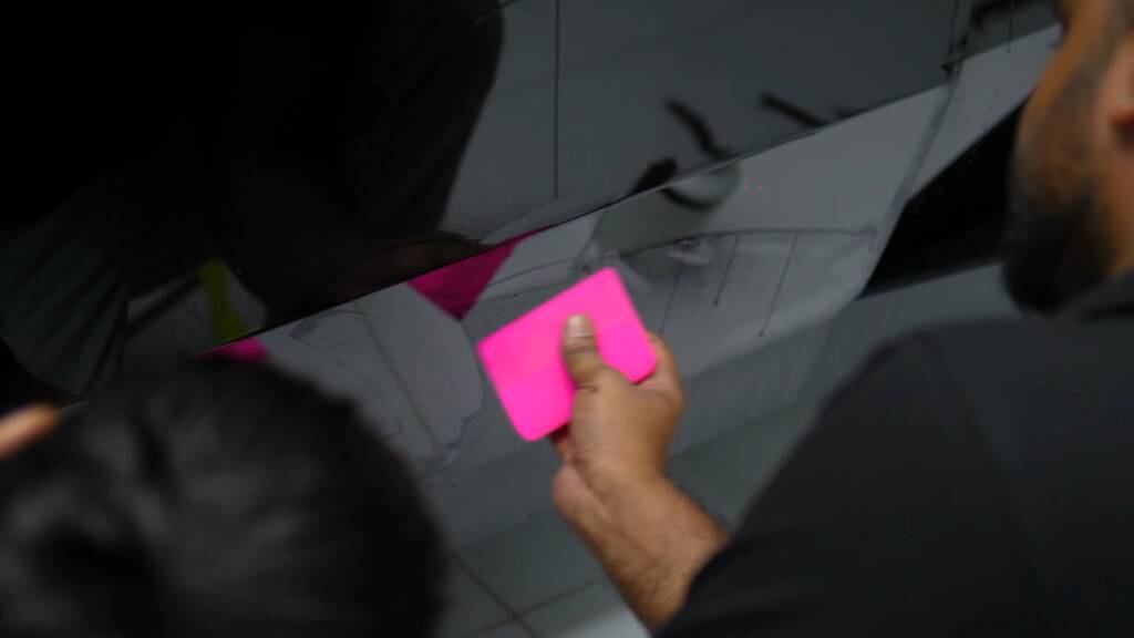 Close-up of a squeegee smoothing gloss black PPF on a Tesla Cybertruck panel