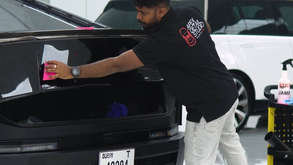 Installer squeegeeing gloss black PPF across the Tesla Cybertruck tailgate