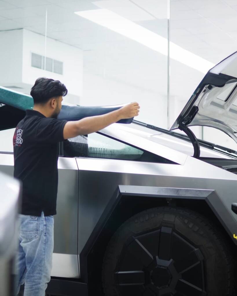 Installer positioning green colour PPF on the rear quarter of a stainless steel Tesla Cybertruck in Dubai