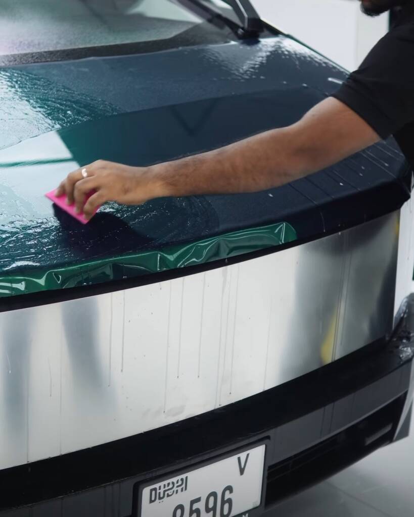Installer squeegeeing green colour change PPF onto the front panel of a Tesla Cybertruck in Dubai