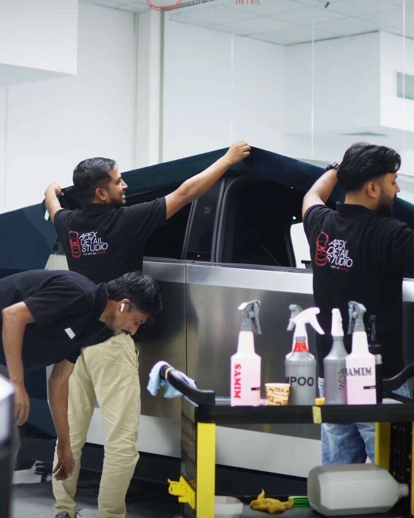 Three Apex Detail Studio installers fitting green colour PPF along the bed side of a Tesla Cybertruck