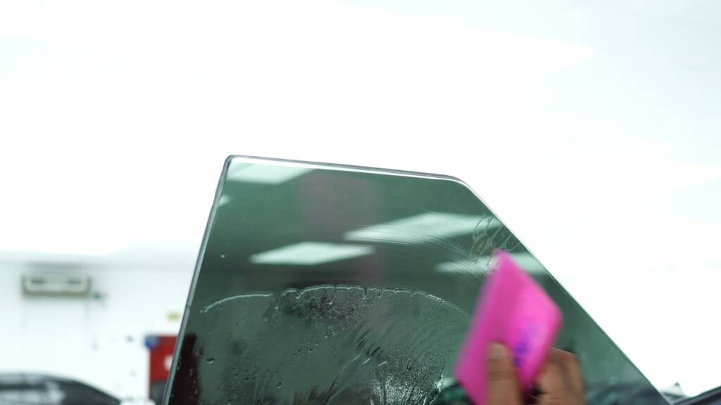 Squeegee pushing water out of Tesla Cybertruck window tint
