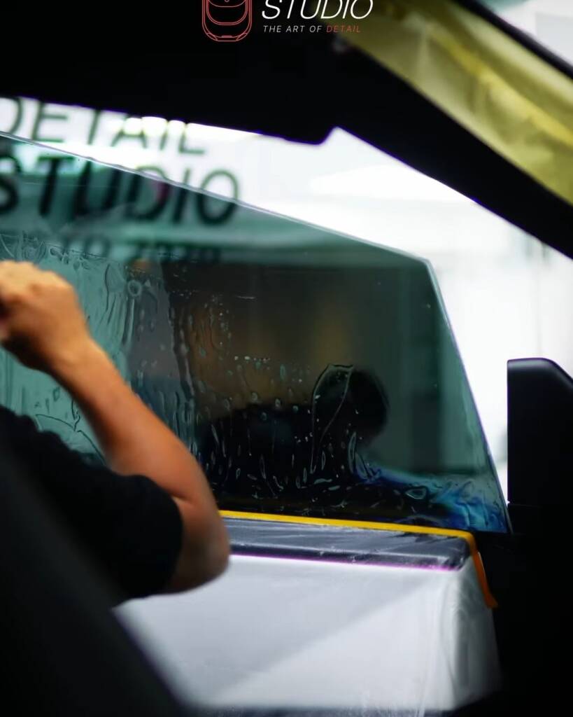 Installer fitting window tint film from inside a Tesla Cybertruck at Apex Detail Studio Dubai