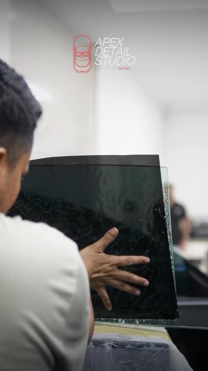 Installer placing a cut tint film on the Tesla Model 3 window in Dubai