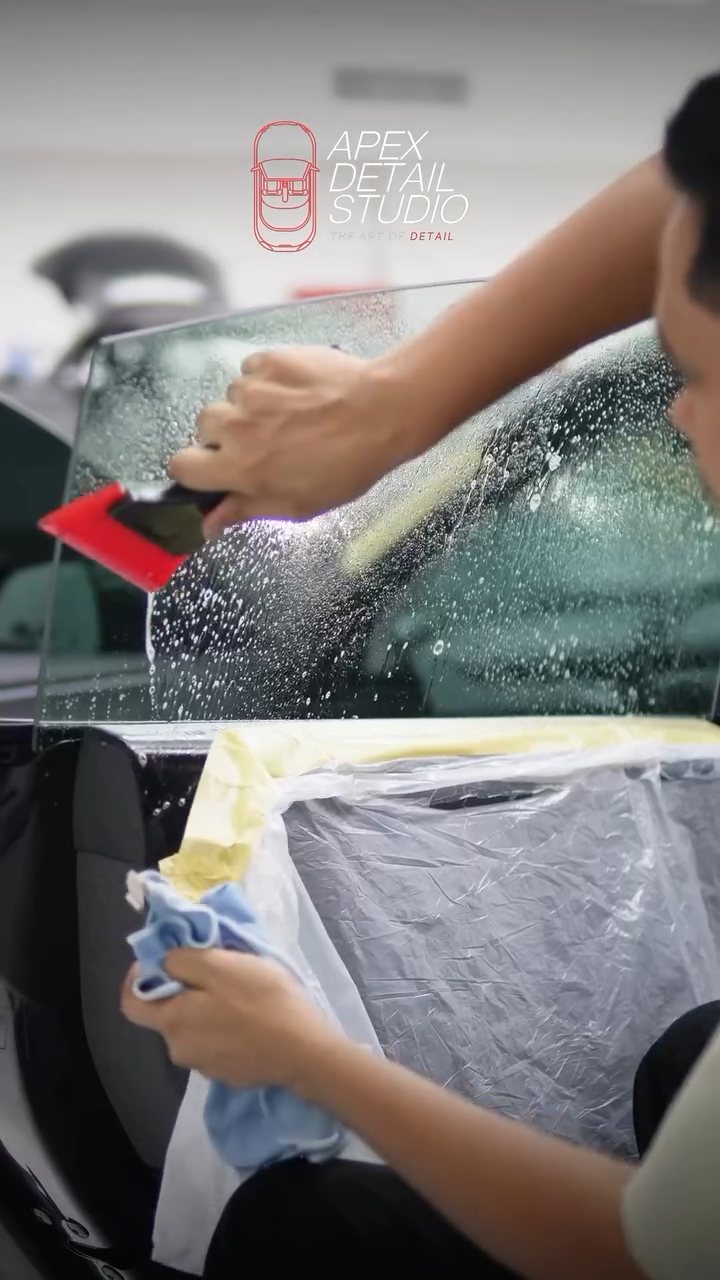 Tint being squeegeed onto the Tesla Model 3 rear door glass in Dubai