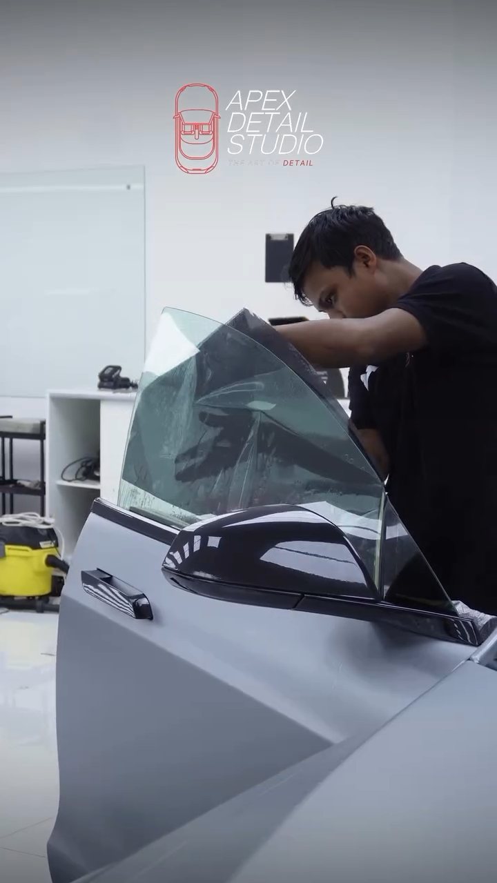 Installer checking the tinted glass on the Tesla Model S Plaid at Apex Detail Studio Dubai
