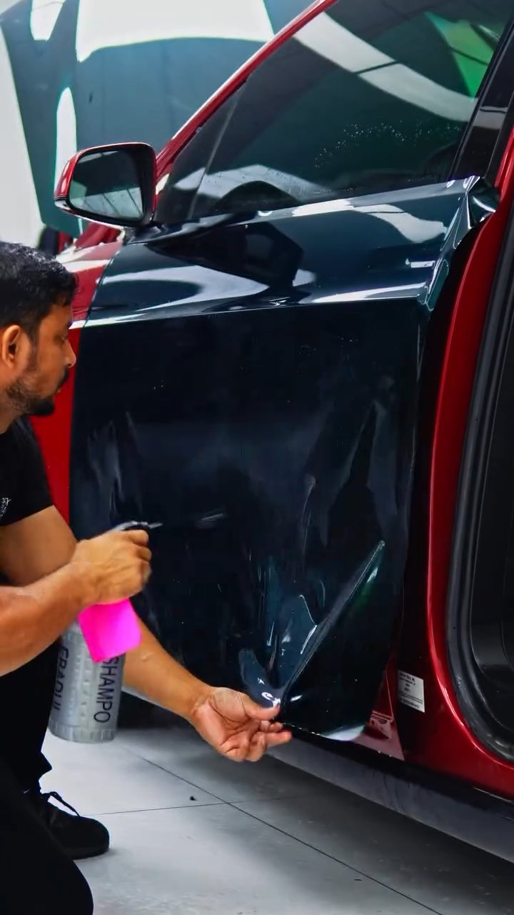 Installer fitting emerald green colour PPF to the Tesla Model X door in Dubai