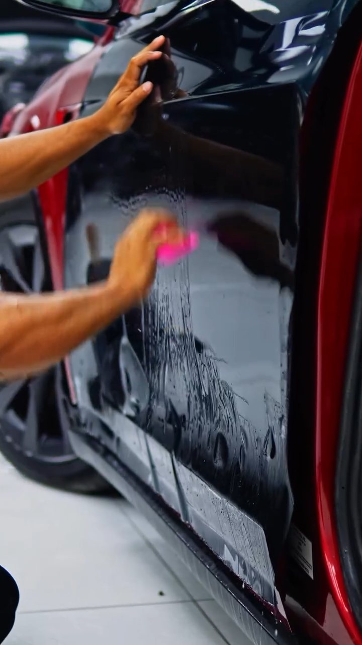 Two installers squeegeeing green colour PPF on the Tesla Model X at Apex Detail Studio Dubai