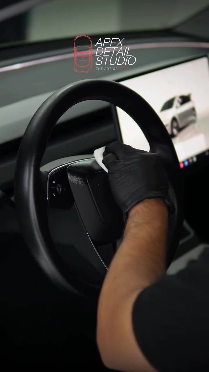 Detailer coating the Tesla Model Y steering wheel at Apex Detail Studio
