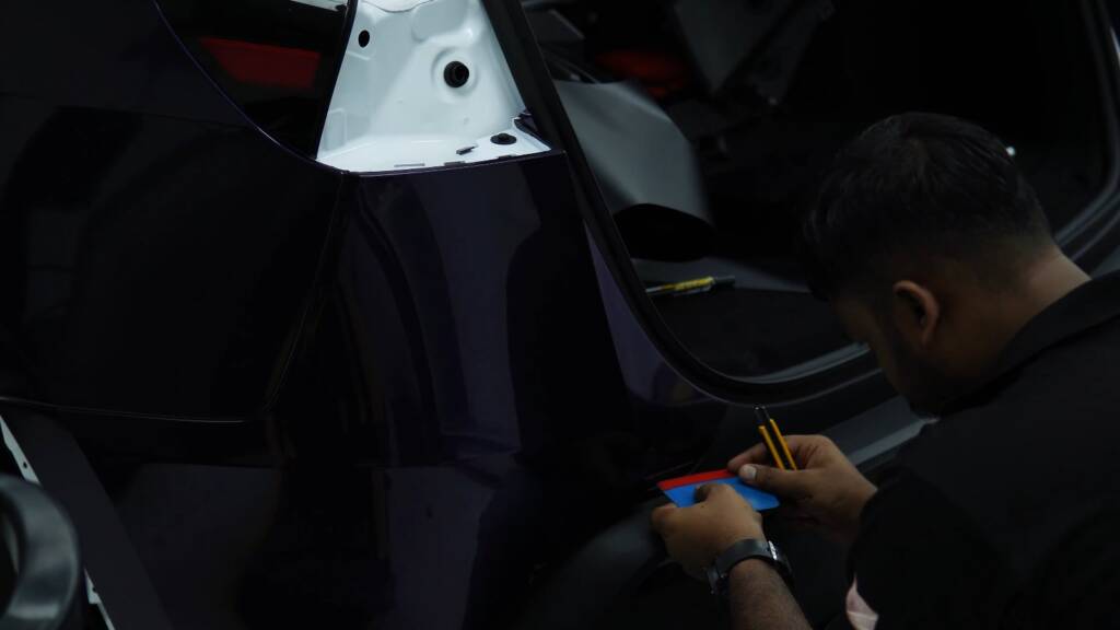 Final checks on a midnight purple Tesla Model Y Juniper