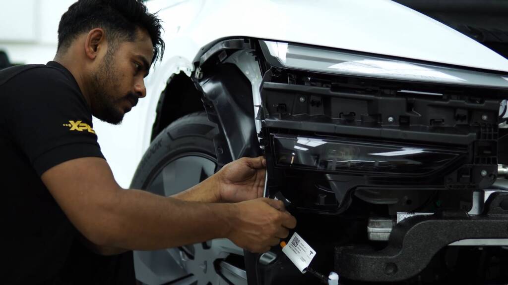 Installer working on a Tesla Model Y Juniper front end during wrap