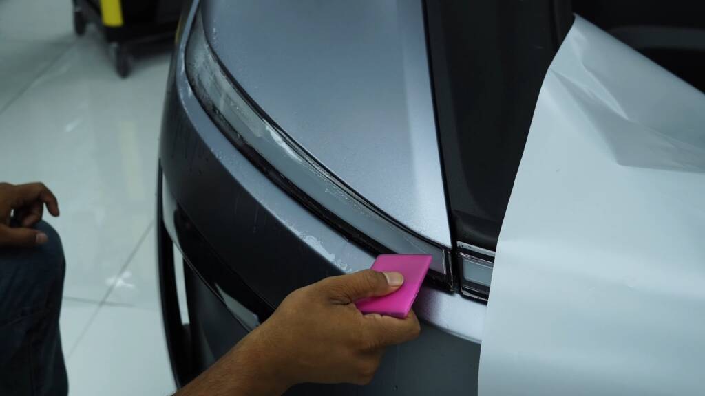 Squeegee on premium satin PPF at a Tesla Model Y Juniper door edge