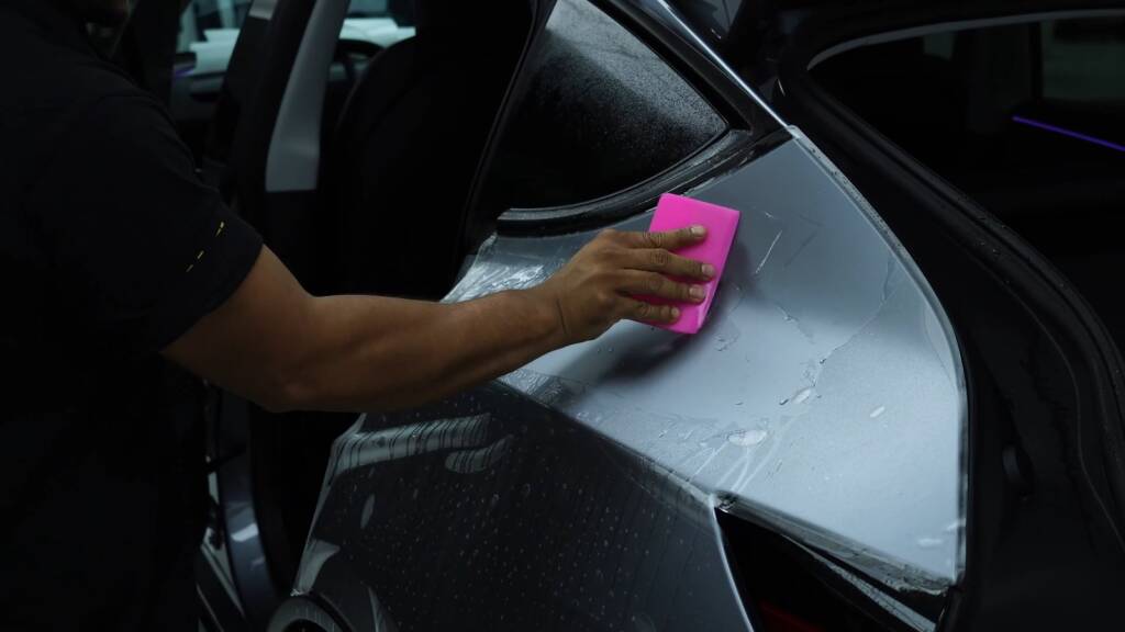 Squeegee on stealth PPF on a Tesla Model Y Juniper rear quarter
