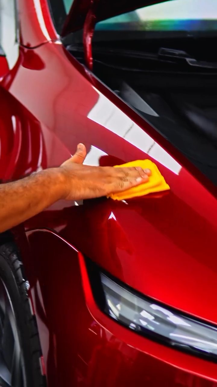 Installer squeegeeing PPF on the red Tesla Model Y Performance front at Apex Detail Studio Dubai