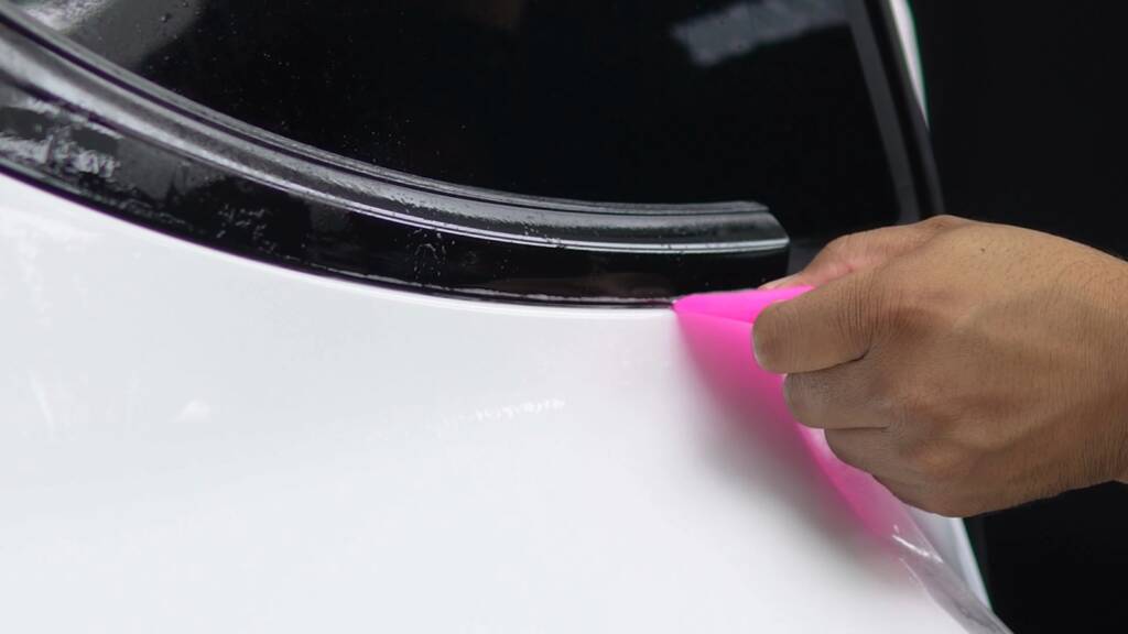 Squeegee working stealth PPF along the light bar of a Tesla Model Y Performance