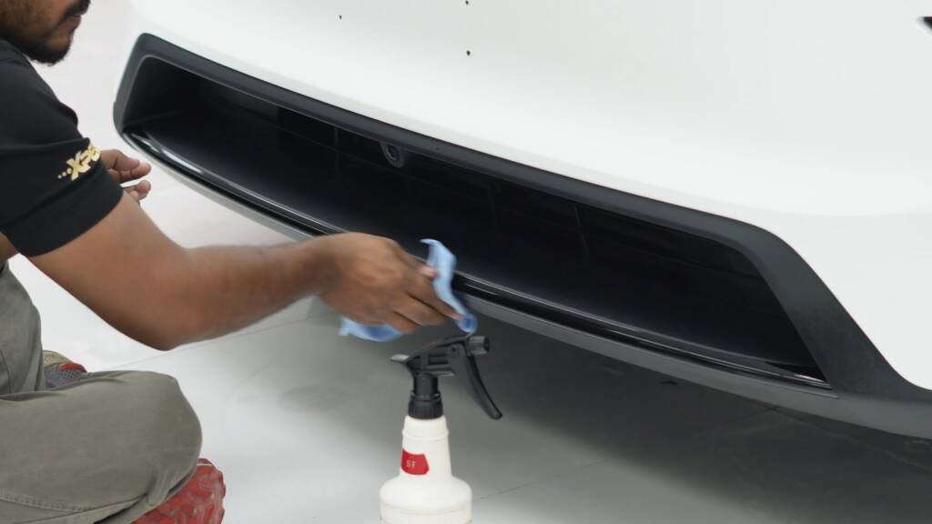 Installer spraying slip solution on the rear bumper of a Tesla Model Y Performance before PPF