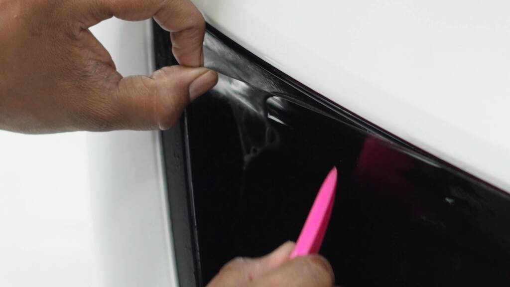 Installer trimming satin PPF around the tail light of a Tesla Model Y Performance