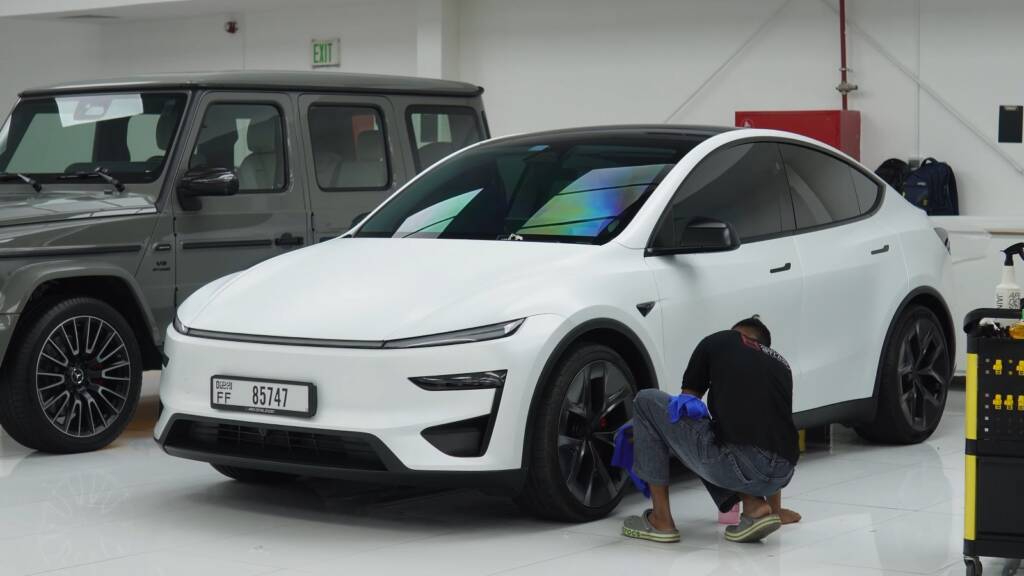 Apex installer checking the satin film along the wheel arch of a white Tesla Model Y Performance