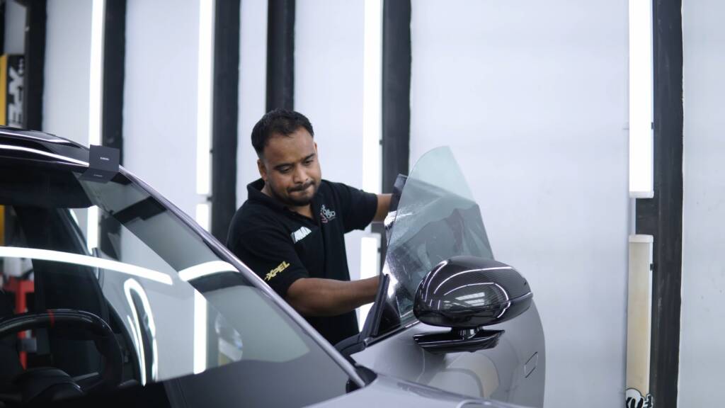 Installer fitting window tint on the side glass of a Xiaomi YU7 Max in Dubai