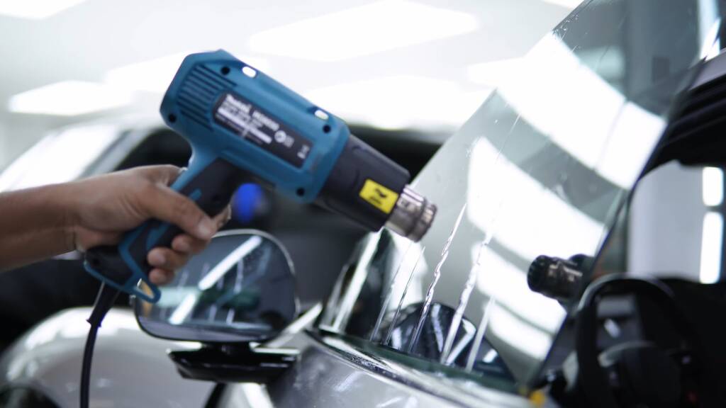 Heat gun shaping window tint film on the glass of a Xiaomi YU7 Max
