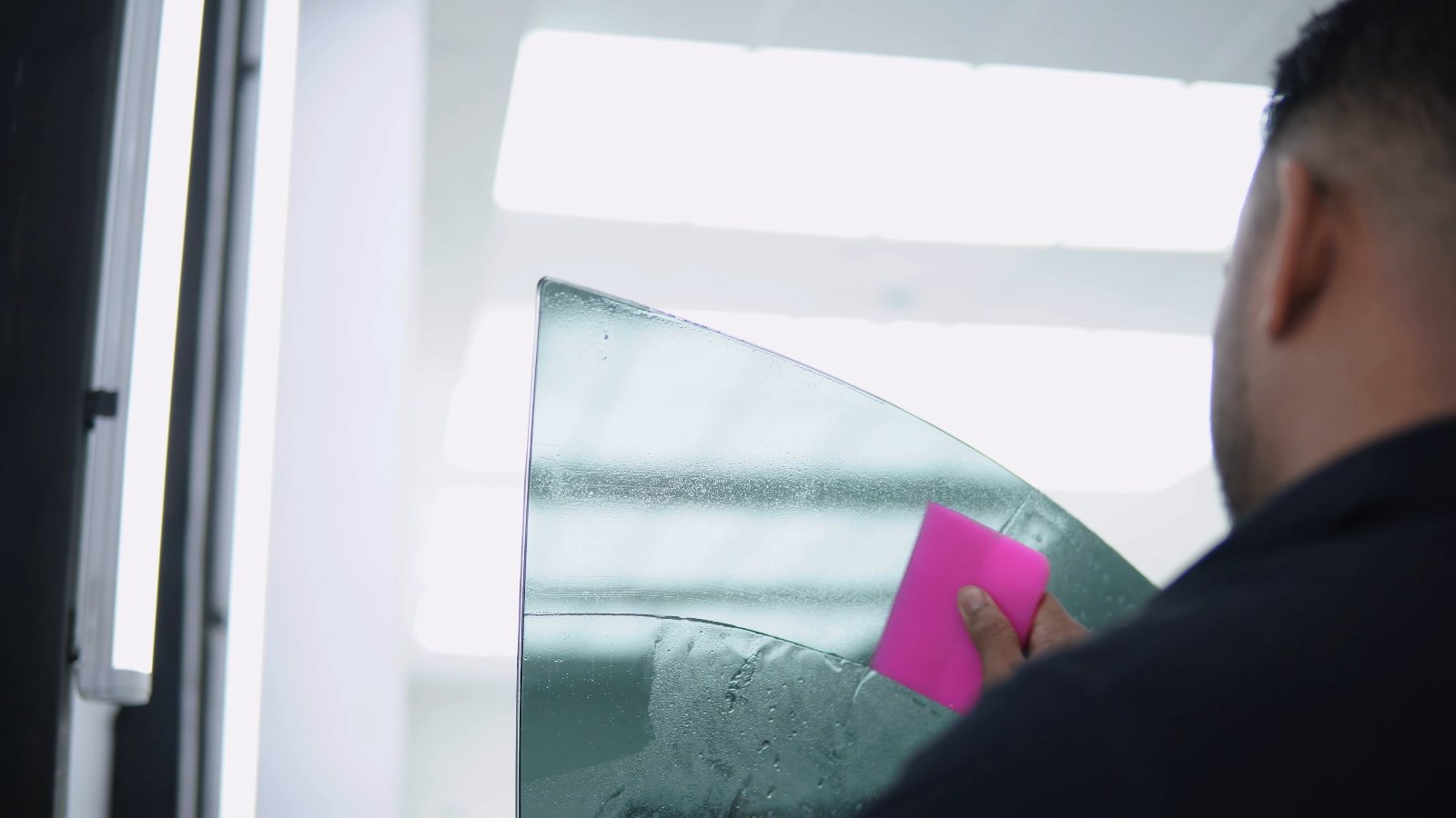 Apex technician squeegeeing heat rejection film onto glass