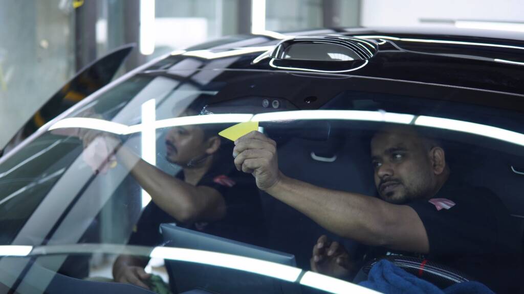 Two installers fitting tint film inside a Xiaomi YU7 Max